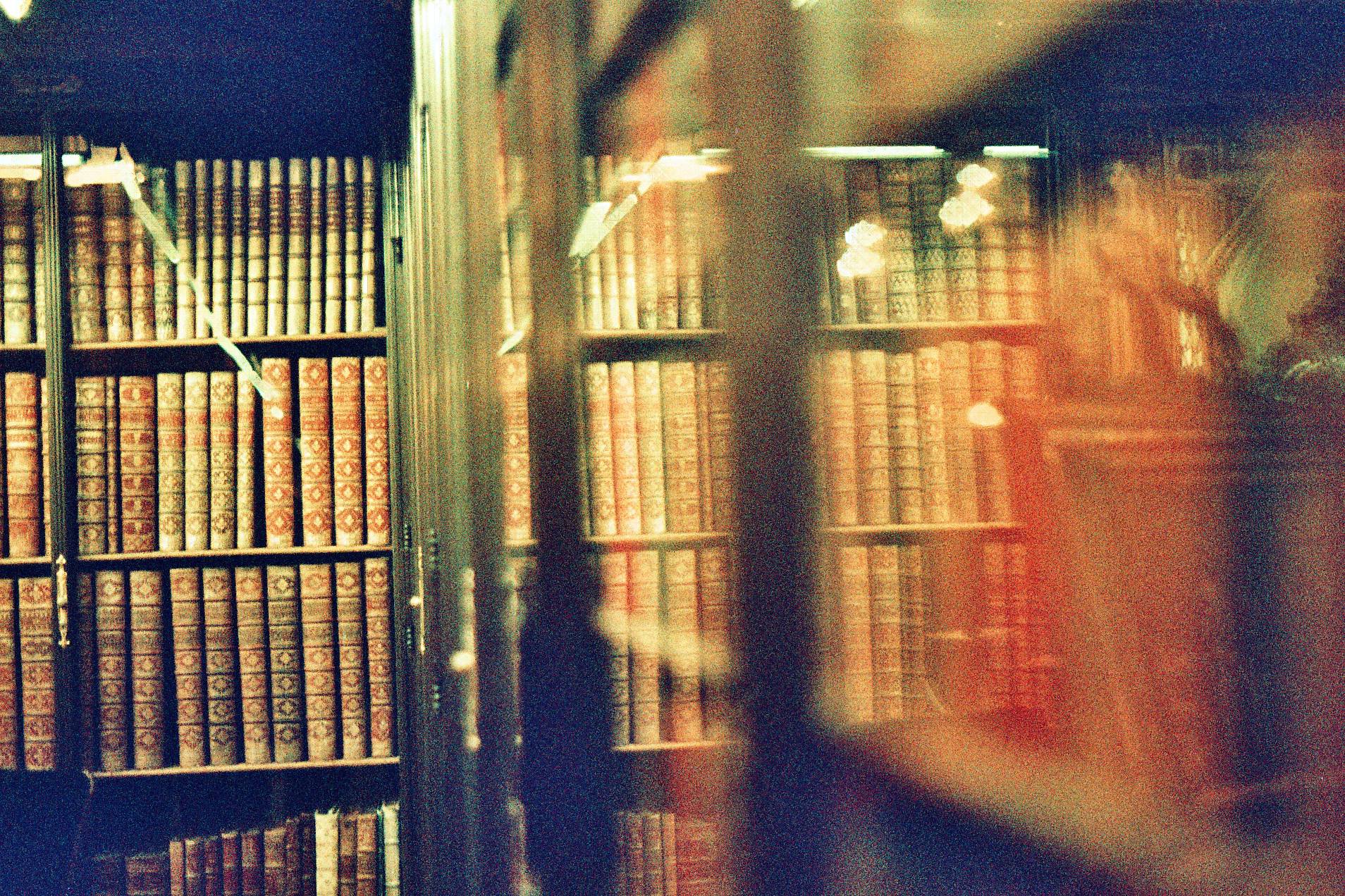 Antique books on library shelves, warm amber film photograph